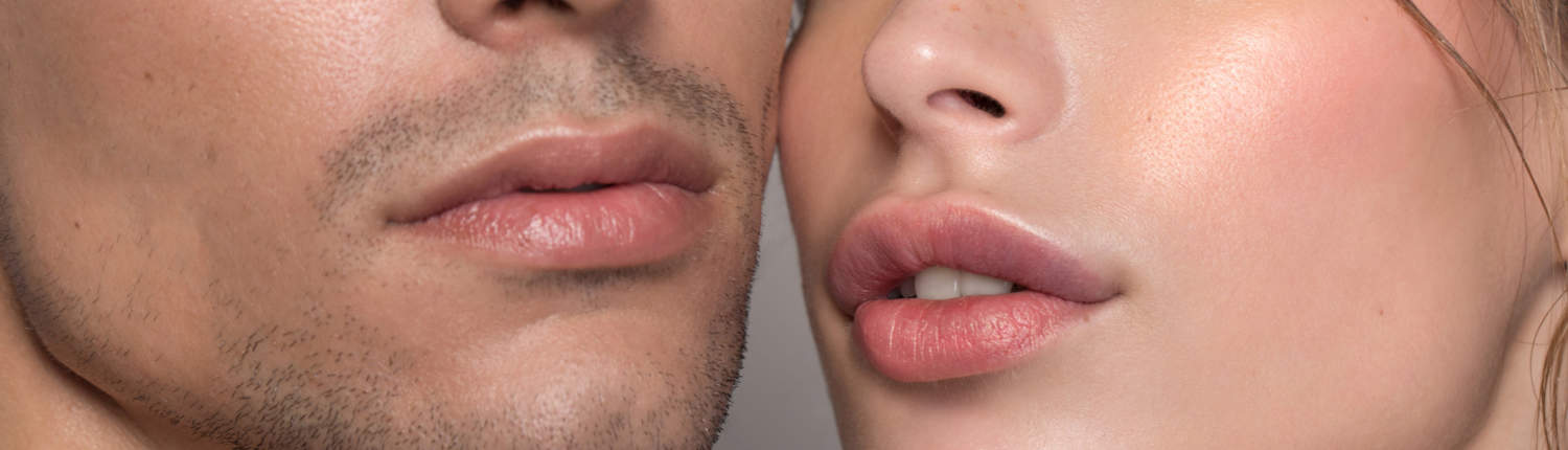 Closeup studio shot of a beautiful young woman and man with freckles skin posing against a grey background, lip enhancers 