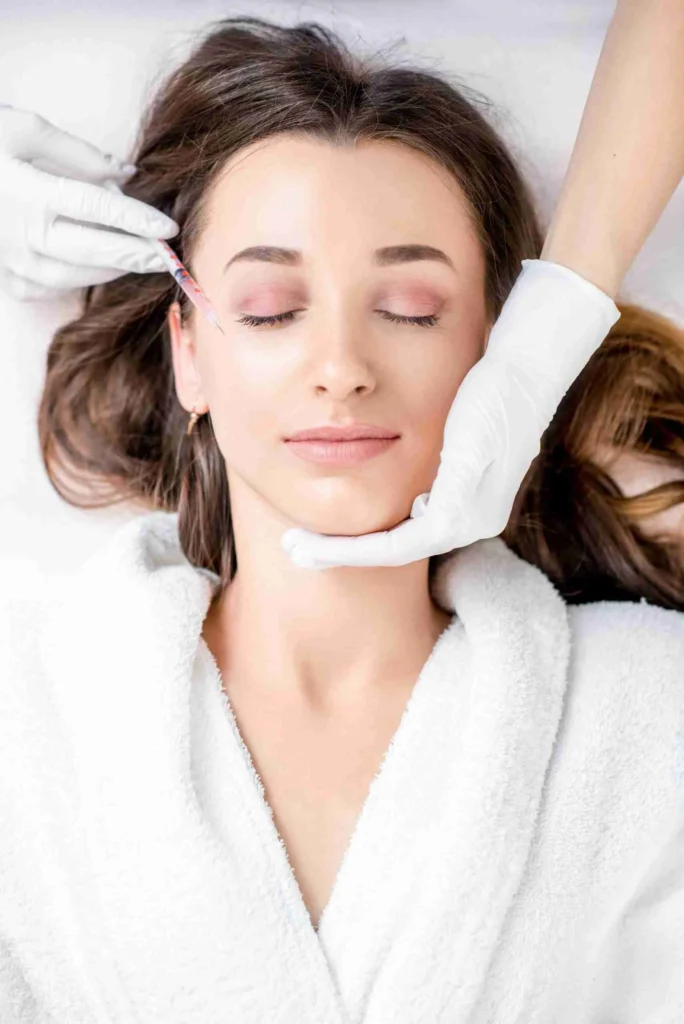 woman receiving botox injection eye zone lying bathrobe medical couch scaled