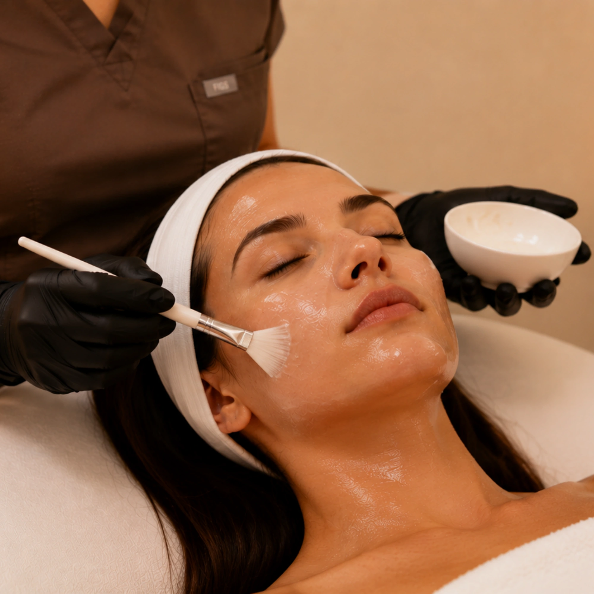 Medical aesthetician applying a professional facial mask during a customized skin care treatment to improve skin health and radiance.
